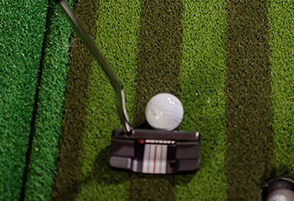 Closeup of a putter and ball on the putting green